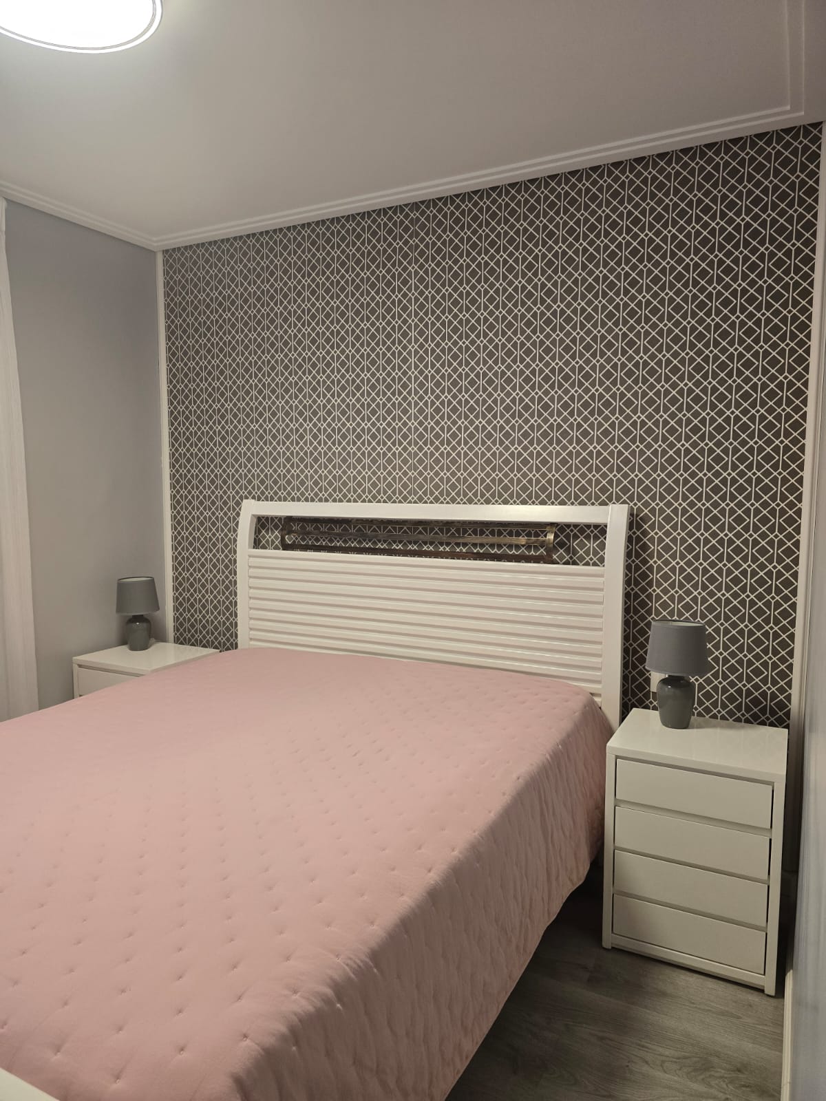 Suíte com cama de casal e papel de parede geométrico do apartamento no Condomínio Alegria, Guarulhos