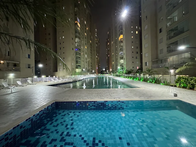 Piscinas iluminadas à noite entre as torres do Condomínio Alegria, Guarulhos